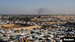 FILE - A general view of a tent camp housing displaced Palestinians, as smoke rises in the distance due to an Israeli ground operation in Khan Younis, as seen from Rafah, January 22, 2024.