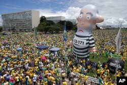 FILE - Demonstrators demand the impeachment of Brazil's President Dilma Rousseff during a rally where a large inflatable doll of former President Luiz Inacio Lula da Silva stands in prison garb in Brasilia, Brazil, March 13, 2016.