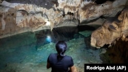 FILE - Maribel Ek, guardian of the cenotes, rests inside the Santa Maria cenote, in Homun, Mexico, Monday, March 4, 2024. (AP Photo/Rodrigo Abd)