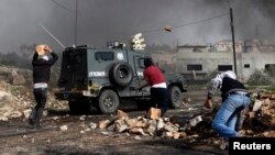 Palestinian protesters throw rocks at an Israeli border police vehicle during clashes at a weekly protest against the nearby Jewish settlement of Kdumim, in the West Bank village of Kfar Kadum, near Nablus, January 25, 2013.