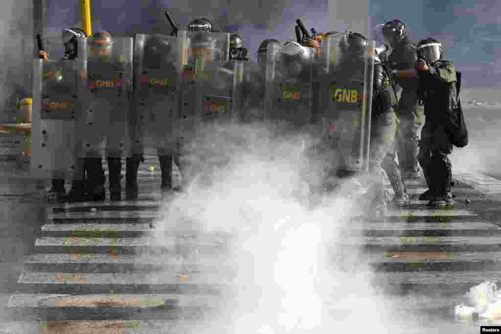 National Guards advance on anti-government protesters during clashes with police at Altamira square in Caracas. Opponents of Venezuela&#39;s socialist government marched to protest against alleged Cuban interference in the armed forces, with clashes breaking out afterwards in a Caracas square, March 16, 2014.