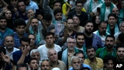 FILE - A supporter of Iranian presidential candidate Masoud Pezeshkian holds up a poster of the reformist during a campaign stop in Tehran, Iran, June 23, 2024.