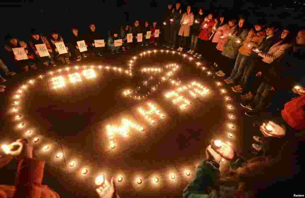 دانشجویان دانشگاه برای مسافران پرواز شماره ۳۷۰ کوآلالامپور به پکن شمع افروخته و دعا می خوانند - یانگژو، چین، ۱۳ مارس ۲۰۱۴