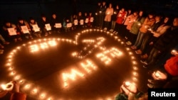 College students light up candles as they pray for passengers of the missing Malaysia Airlines MH370 plane in Yangzhou, Jiangsu province, March 13, 2014.