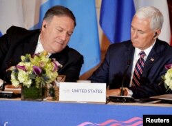 U.S. Secretary of State Mike Pompeo, left, leans in as Vice President Mike Pence makes a note during the Second Conference on Prosperity and Security in Central America, in Washington, Oct. 11, 2018.