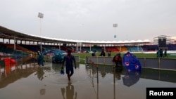 A man walks amidst rain waters before a cricket match between Pakistan and Sri Lanka, at the National Stadium in Karachi, Pakistan, Sept. 27, 2019.