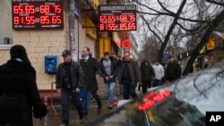 Signs advertising currencies are illuminated next to the exchange office in Moscow, where the ruble staged a morning rally before rolling back to historic lows.