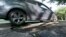 FILE - An automobile drives over a pothole in Bloomfield Township, Michigan.