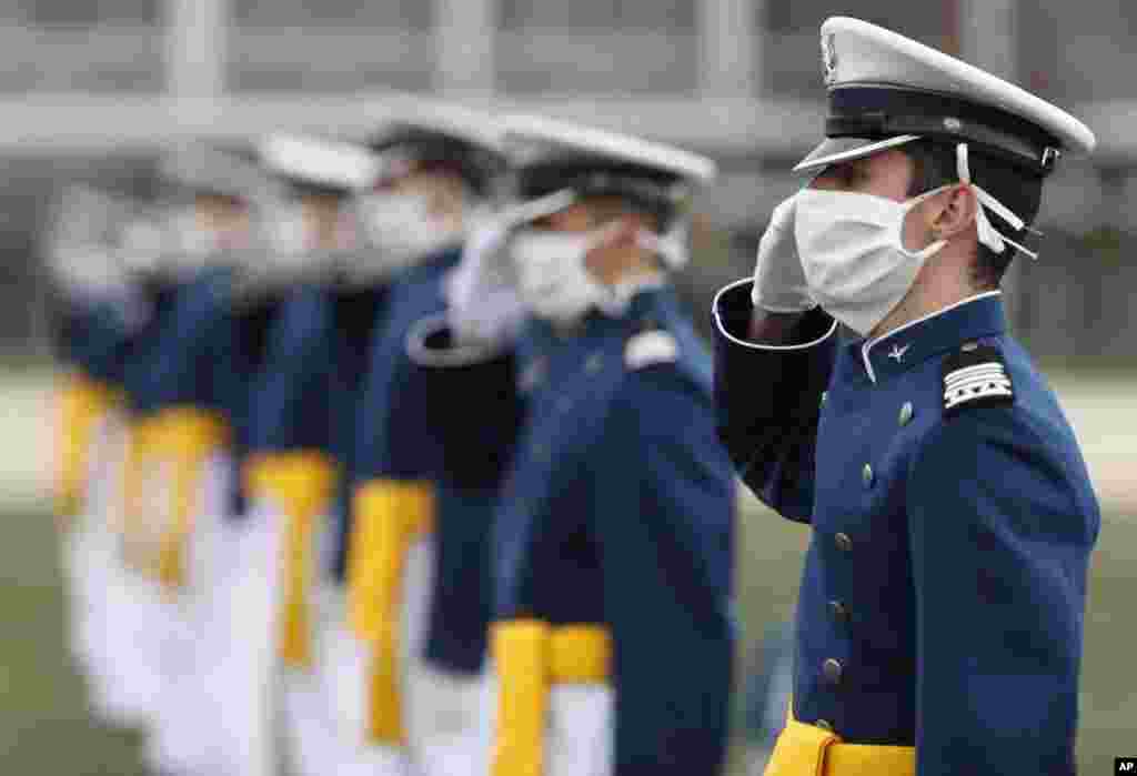 Los cadetes usan sus máscaras protectoras mientras hacen el saludo militar como parte de su ceremonia de graduación, el sábado 18 de abril de 2020.