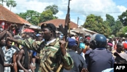 Security forces try to protect a Nigerian man accused of kidnapping a child from an angry crowd in Bissau, Oct. 8, 2013.