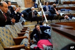 People shelter in the House gallery as protesters try to break into the House Chamber at the U.S. Capitol on Wednesday, Jan. 6, 2021, in Washington. (AP Photo/Andrew Harnik)