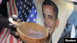 A person holds a bowl of porridge against a poster of U.S. President Barack Obama as Kenyans celebrate his re-election in Nairobi's Kibera slums on November 7, 2012.