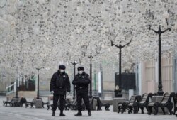 Russian law enforcement officers wearing protective masks stand guard in a street, after the city authorities announced a partial lockdown to prevent the spread of coronavirus disease (COVID-19), in central Moscow, March 30, 2020.