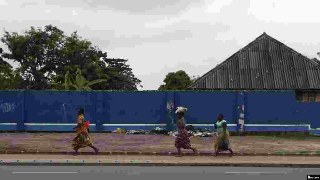 Congolese women run for safety along a deserted street during a clash near the state television headquarters in Kinshasa, Dec. 30, 2013.