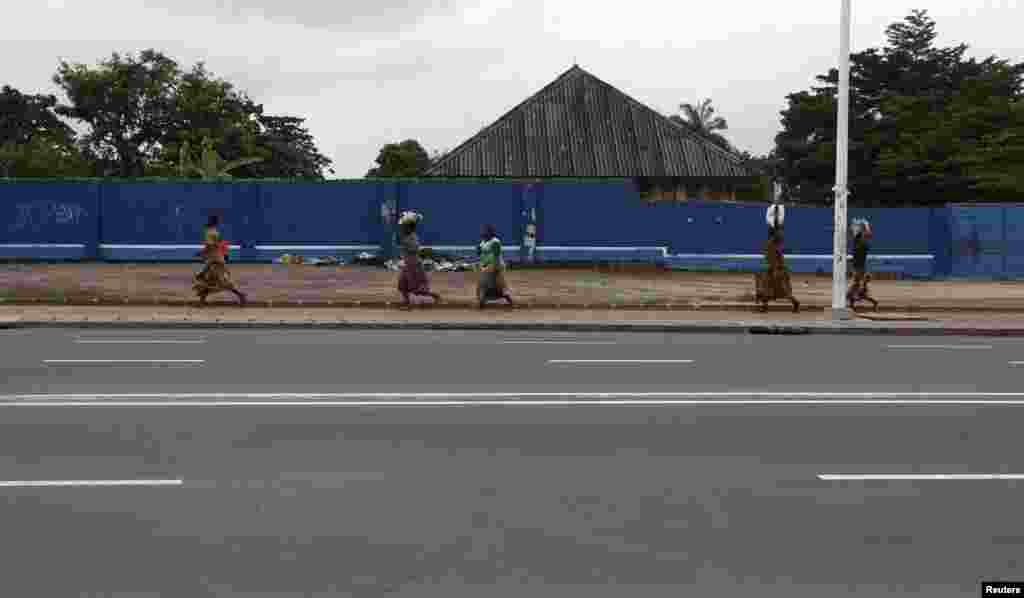 Congolese women run for safety along a deserted street during a clash near the state television headquarters in Kinshasa, Dec. 30, 2013. 