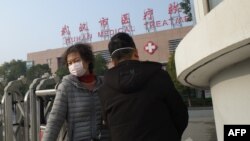 A woman (L) leaves the Wuhan Medical Treatment Centre, where a man who died from a respiratory illness was confined, in the city of Wuhan, Hubei province, on January 12, 2020.