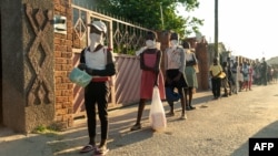 FILE - People line up for a food handout amid the coronavirus pandemic, in Chitungwizaon, Zimbabwe, May 5, 2020.