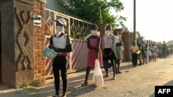 FILE - People line up for a food handout amid the coronavirus pandemic, in Chitungwiza, Zimbabwe, May 5, 2020.