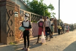 FILE - People line up for a food handout amid the coronavirus pandemic, in Chitungwizaon, Zimbabwe, May 5, 2020.