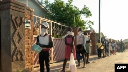 FILE - People line up for a food handout amid the coronavirus pandemic, in Chitungwiza, Zimbabwe, May 5, 2020.
