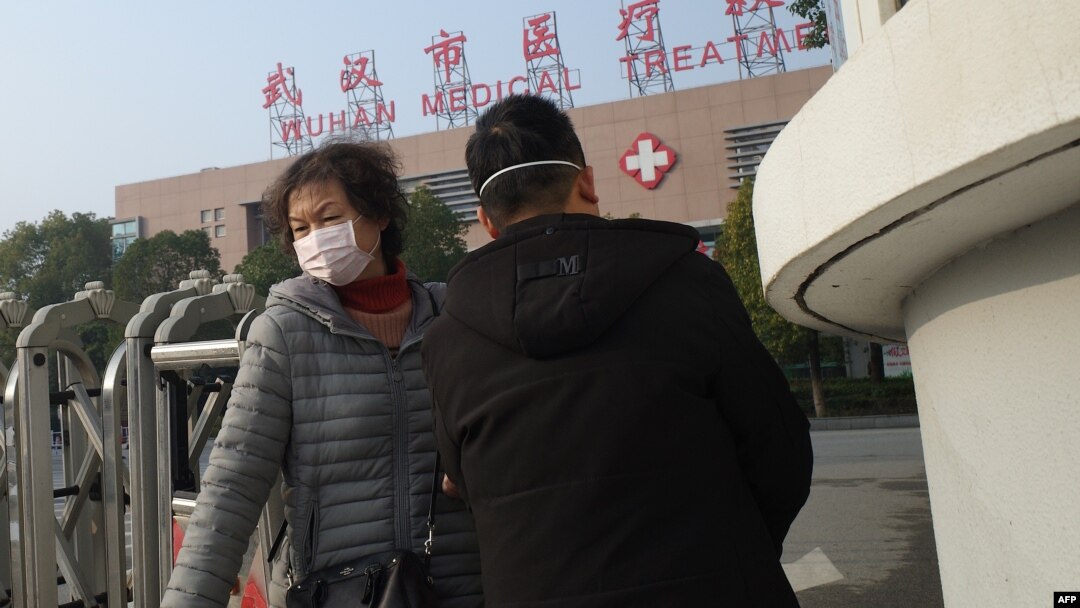 Seorang perempuan (kiri) meninggalkan Pusat Kesehatan Wuhan, di mana seorang pria yang dirawat karena penyakit pernafasan, meninggal, di Kota Wuhan, Provinsi Hubei, 12 Januari 2020. (Foto: AFP)