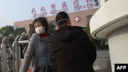 Seorang perempuan (kiri) meninggalkan Pusat Kesehatan Wuhan, di mana seorang pria yang dirawat karena penyakit pernafasan, meninggal, di Kota Wuhan, Provinsi Hubei, 12 Januari 2020. (Foto: AFP)