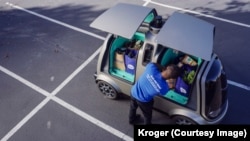 A man unloads goods from an unmanned vehicle known as the R1 in this handout photo provided by Kroger.