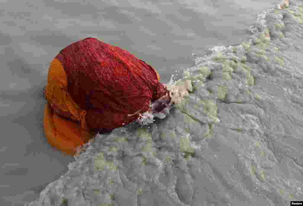 A female Hindu pilgrim takes a dip at the confluence of the Ganges River and the Bay of Bengal at Sagar Island, south of Kolkata, India, Jan. 14, 2013. Hindu monks and pilgrims are making an annual trip to Sagar Island for the one-day festival of &quot;Makar Sankranti.&quot;