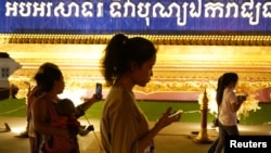 Sejumlah orang berjalan sambil menggunakan ponsel mereka di Phnom Penh, Kamboja, 18 Februari 2021. (Foto: Reuters)