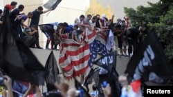 Protesters destroy an American flag pulled down from the U.S. embassy in Cairo, September 11, 2012.