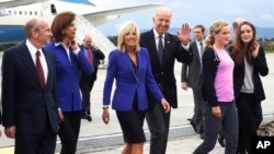 U.S. Vice President Joe Biden, third from right, waves to reporters accompanied by his wife Jill Biden, third from left, two of their granddaughters and Colombia's Foreign Minister Maria Angela Holguin, second from left, after their arrival to a military airport in Bogota, Colombia, Sunday, May 26, 2013.