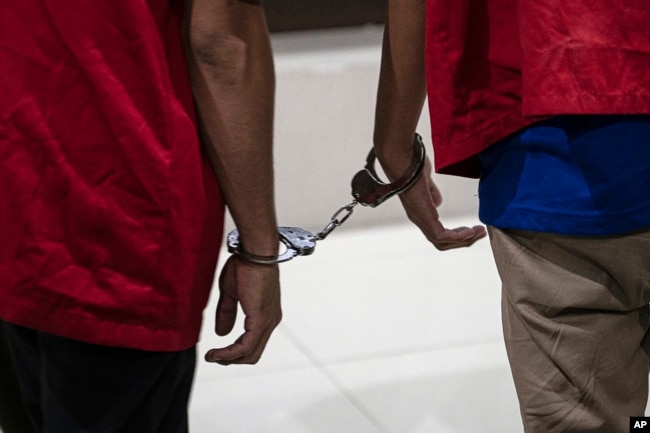 Dua pria yang dihukum karena melakukan hubungan seks sesama jenis berdiri dengan tangan diborgol bersama setelah diadili di pengadilan Syariah di Banda Aceh, Indonesia, Senin, 24 Februari 2025. (Reza Saifullah/AP)