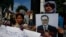A Cambodian opposition party supporter, right, holds a portrait photo of an opposition senator Hong Sok Hour during a protest in front of the Phnom Penh Municipal Court, in Phnom Penh, Cambodia, Saturday, Aug. 15, 2015. 