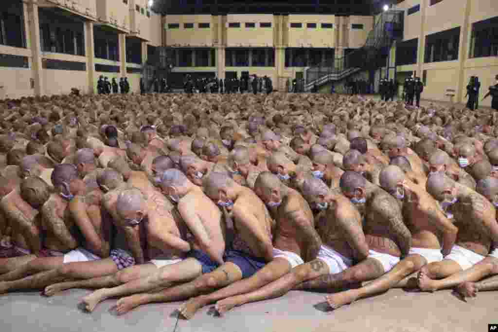 In this photo released by the El Salvador Presidential Press Office, inmates are lined up during a security operation under the watch of police at the Izalco prison in San Salvador, El Salvador, April 25, 2020. Authorities crammed the face mask-