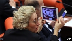 FILE - Melda Onur, an opposition Republican People's Party lawmaker, records debates during a special session of the parliament in Ankara, Turkey, March 19, 2014. 