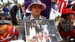 A Cambodian land-grabbing affected villager, center, holds a picture of U.S. President Barack Obama and his family in front of U.S. Embassy in Phnom Penh, Cambodia, Tuesday, March 17, 2015. 