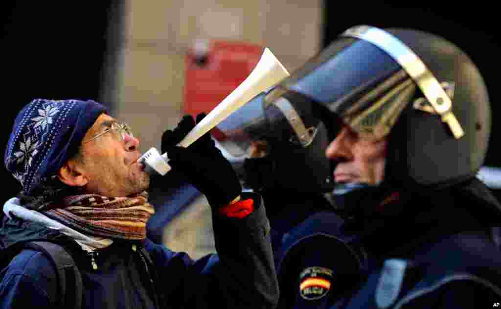 A demonstrator blows a horn in front of Spanish riot police during a strike against government austerity measures in Pamplona, Spain, November 14, 2012. 