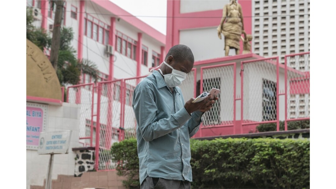 FILE - A man wears a mask while walking outside the entrance to the Yaounde General Hospital in Yaounde on March 6, 2020.