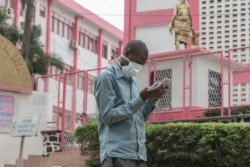 FILE - A man wears a mask while walking outside the entrance to the Yaounde General Hospital in Yaounde on March 6, 2020.