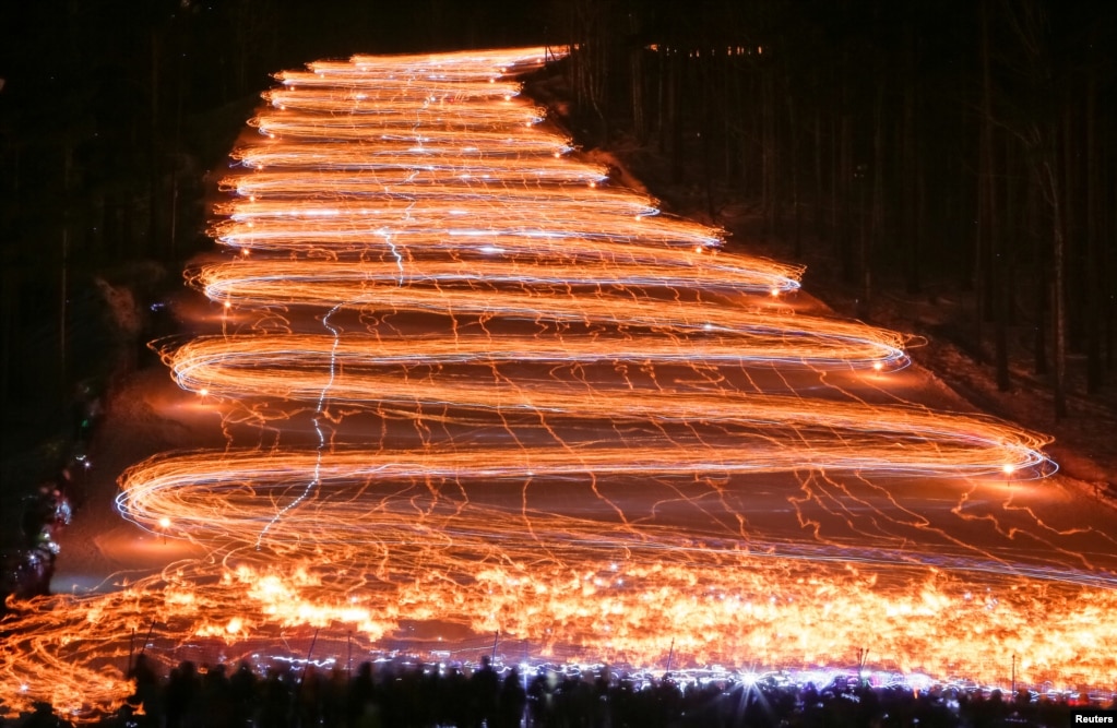 Cientos de esquiadores y practicantes de snowboard descienden de una pendiente mientras sostienen antorchas y linternas encendidas en la ciudad siberiana de Zheleznogorsk, al noreste de Krasnoyarsk, Rusia, el 26 de febrero de 2017.