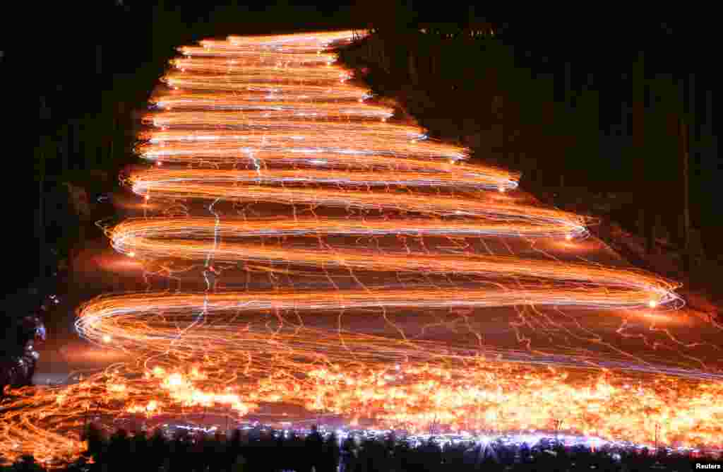 Hundreds of skiers and snowboarders descend from a slope while holding lit torches and flashlights in the Siberian town of Zheleznogorsk, northeast of Krasnoyarsk, Russia.