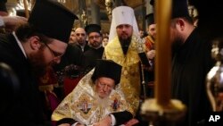 Ecumenical Patriarch Bartholomew I, center, signs the "Tomos" decree of autocephaly for the Ukrainian church during the ceremony at the Patriarchal Church of St. George in Istanbul, Jan. 5, 2019.