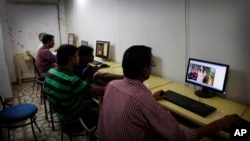 FILE - Indian youth use the internet at a cyber cafe in Allahabad, India. The hotline is a simple online form which the public, police, internet companies and victims can access in either Hindi or English.