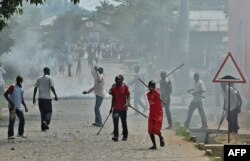 FILE - Members of the Imbonerakure, armed with sticks, chase protesters opposed to the Burundian president's third term in the Kinama neighborhood of Bujumbura, May 25, 2015.