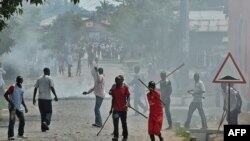 FILE - Members of the Imbonerakure, armed with sticks, chase protesters opposed to the Burundian president's third term in the Kinama neighborhood of Bujumbura. Taken 5.25.2015