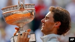 Petenis Spanyol, Rafael Nadal mengangkat trophy kejuaraan grand slam Perancis Terbuka yang ke-9, setelah menang atas Novak Djokovic di Roland Garros, Paris, Minggu (8/6). 