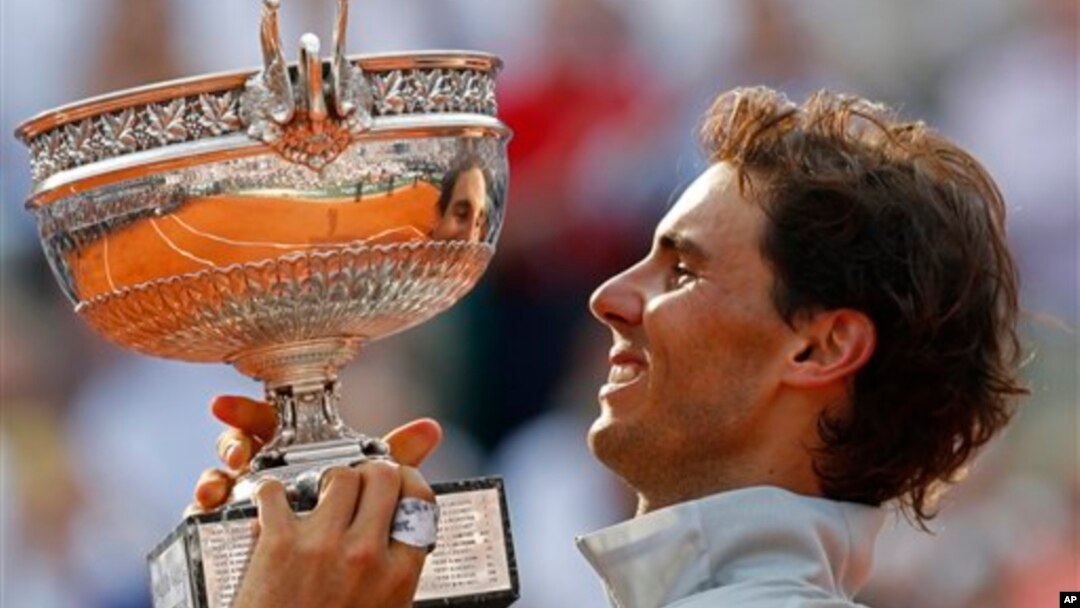 Petenis Spanyol, Rafael Nadal mengangkat trophy kejuaraan grand slam Perancis Terbuka yang ke-9, setelah menang atas Novak Djokovic di Roland Garros, Paris, Minggu (8/6). 