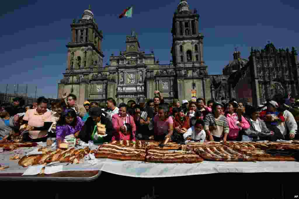 En el centro de Ciudad de México, la gente espera en la víspera de la Epifanía a que le sirvan un pedazo de una Rosca de Reyes gigante que tradicionalmente se prepara este día como parte de las celebraciones del Día de los Reyes Magos. &nbsp;