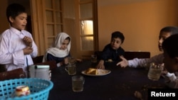 Samira, 9, and other children share tea and bread for breakfast at the orphanage before going to school in Kabul, Afghanistan, October 12, 2021. (REUTERS/Jorge Silva) 