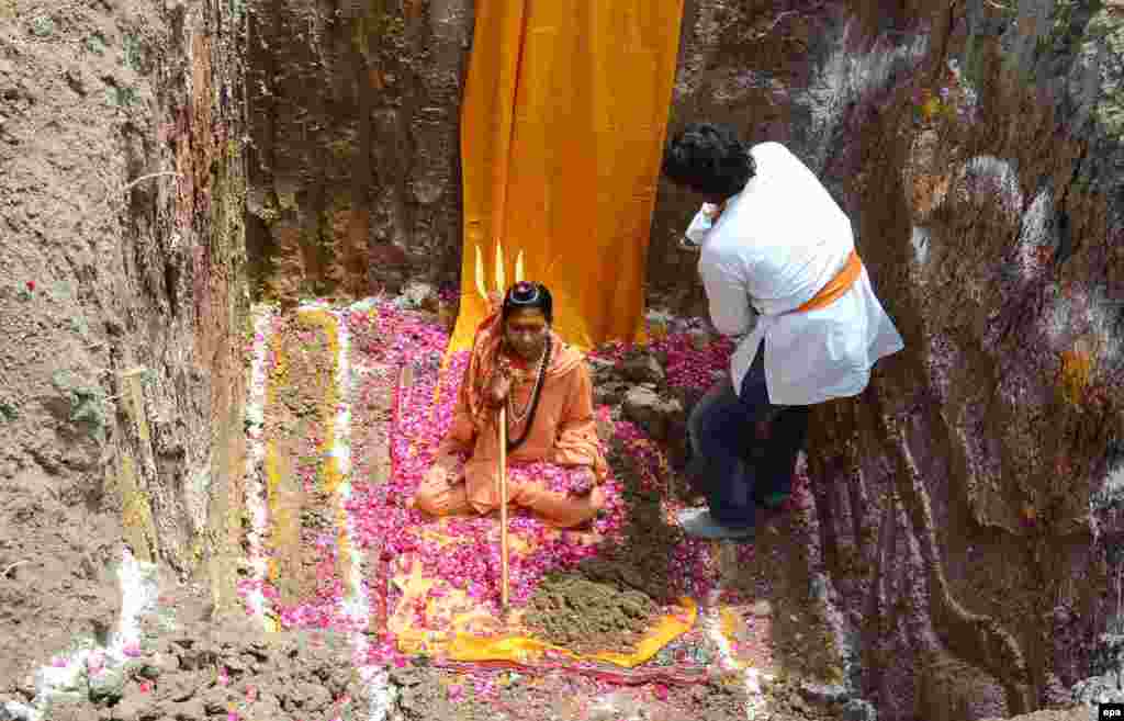 Indian devotees of Trikal Bhawanta casting rose petals before a burial ritual during the month-long Simhastha Kumbh Mela festival in Ujjain, some 180 km from Bhopal. Trikal Bhawanta asked her devotees to bury her alive in protest to being denied permission to take a holy dip during the Kumbh mela, a news report said.